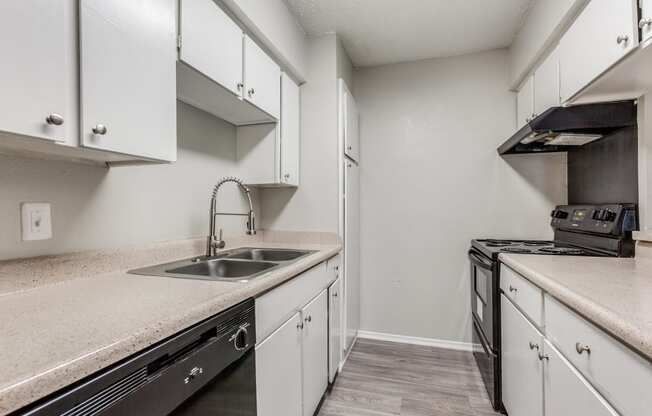 an empty kitchen with white cabinets and a black stove and sink