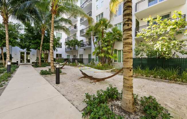 a hammock in the sand outside of an apartment building