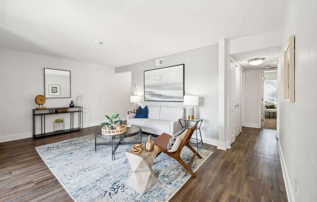 A living room with a white couch and a blue rug.