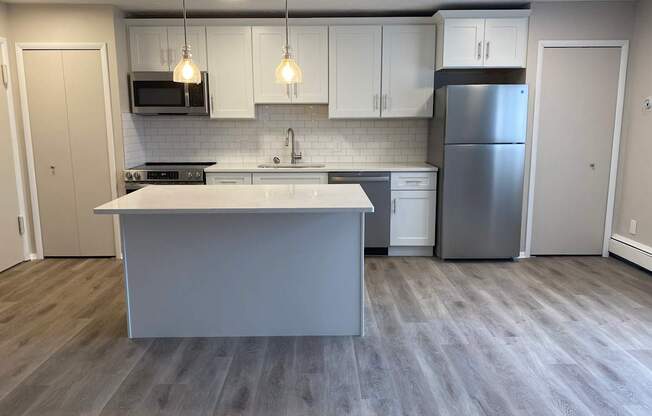 A kitchen with a white island and a refrigerator.