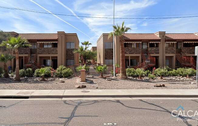 A sunny day at a residential area with two buildings and palm trees.