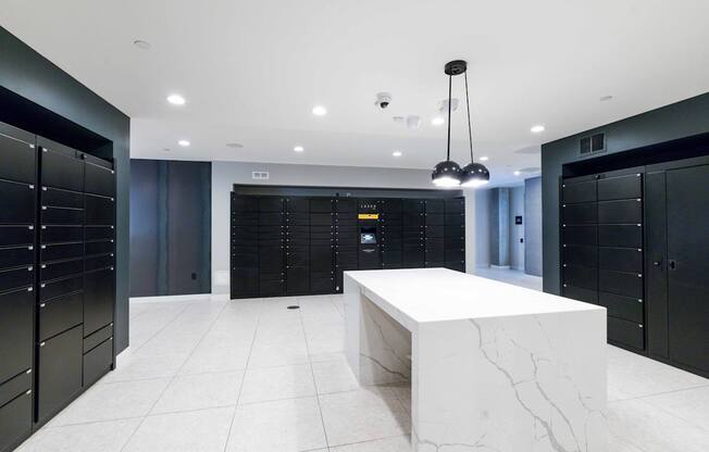 A white marble table is in the middle of a room with black lockers on the walls.