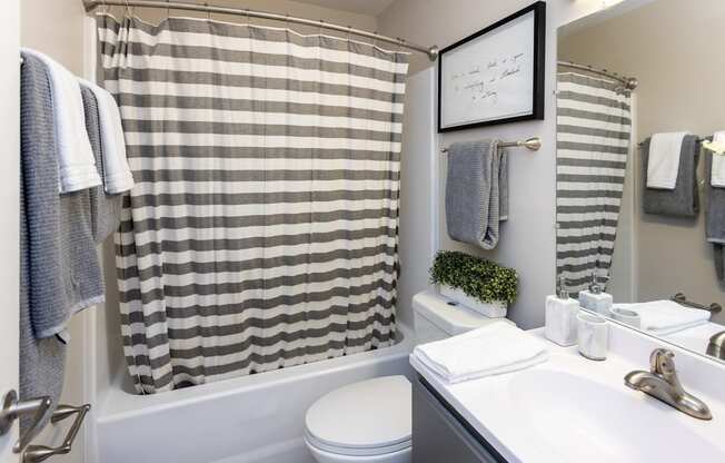 a bathroom with a white sink and toilet next to a bathtub with a shower curtain and
