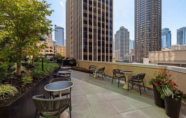 a rooftop patio with tables and chairs and a view of the city