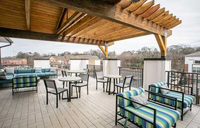 A wooden patio with a striped couch and chairs.