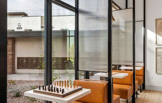 A chess board is set up on a table in front of a glass wall.