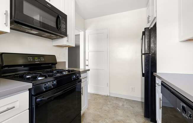 a renovated kitchen with black appliances and white cabinets and a black refrigerator