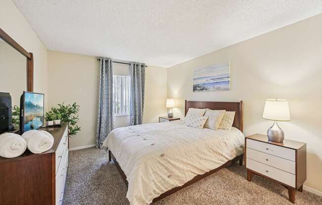 A bedroom with a large bed, a nightstand, and a dresser.