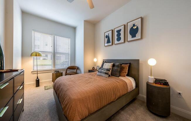 A bedroom with two windows, carpet flooring, and a ceiling fan.