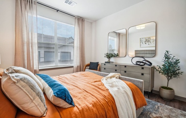 a bedroom with a bed and a dresser with a mirror