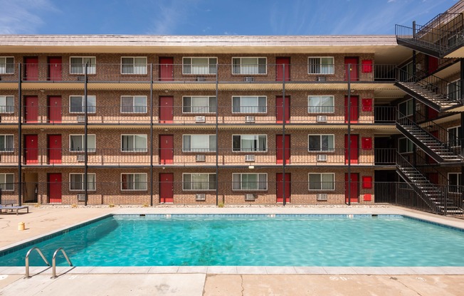 the pool is in front of a red brick building with a swimming pool