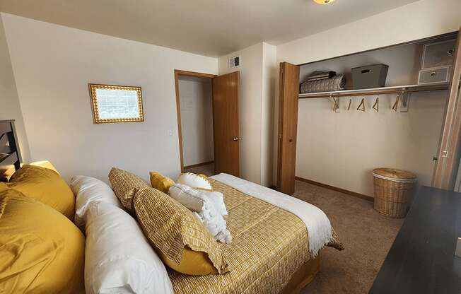 A bedroom with a bed covered in yellow and white bedding.