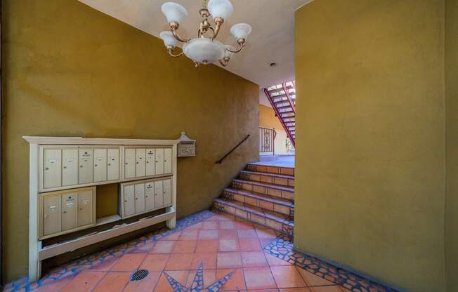 a hallway with a staircase and a yellow wall and a chandelier