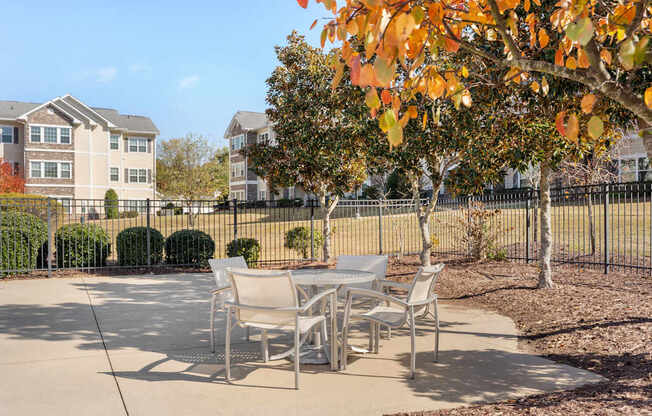A patio with a table and chairs is surrounded by a black fence.