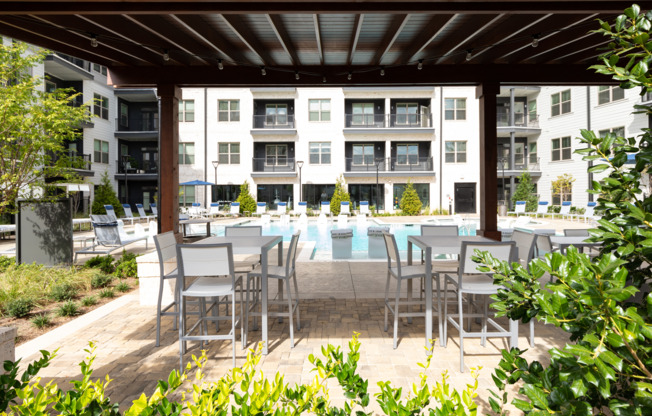 Outdoor lounge at the pool at our apartments in Atlanta, featuring a shade structure with chairs and tables under it.