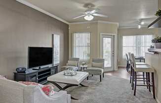 a living room with a ceiling fan and a flat screen tv