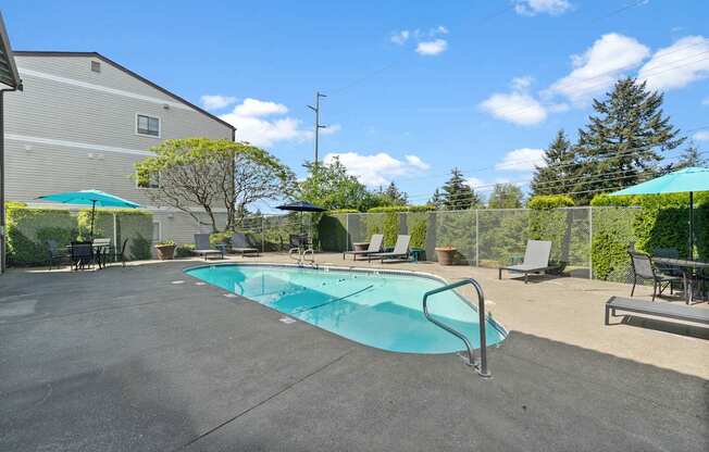 A small pool in a backyard with a table and chairs.