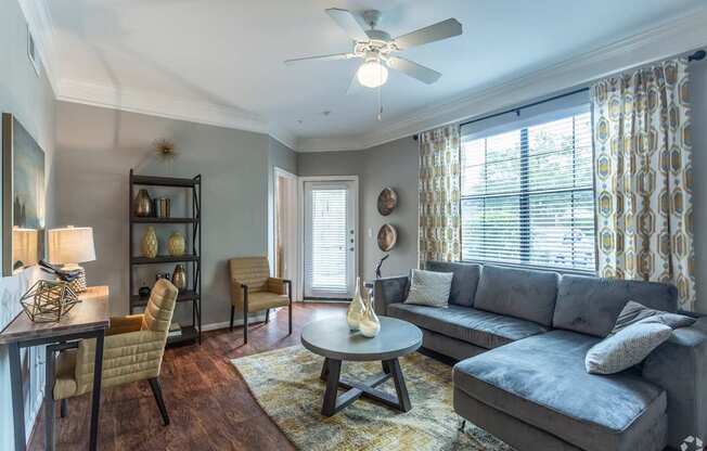 A living room with a grey couch, a wooden coffee table, and a ceiling fan.