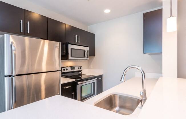kitchen with stainless steel refridgerator, quartz counters, oven and microwave