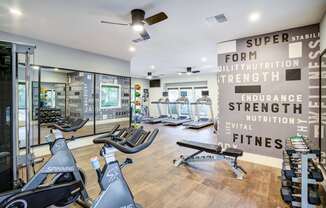 A gym with a row of stationary bikes and a wall of motivational words.