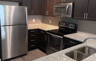 Kitchen with espresso cabinets, double sinks at Flats on 4th Apartments in Birmingham, AL