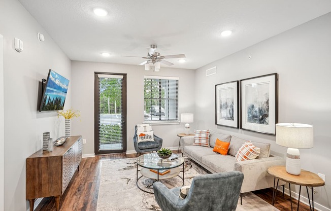 a living room with a couch and chairs and a ceiling fan