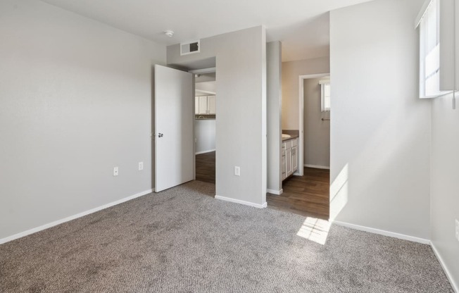 an empty living room with a hallway to a bedroom and a bathroom