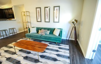 a living room with a green couch and a cowhide rug