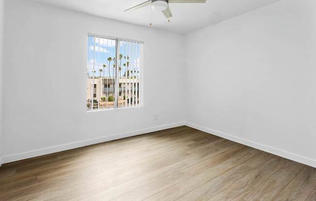 A room with a window overlooking a building with palm trees.
