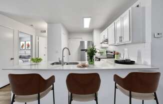 a kitchen with white cabinets and a counter with three chairs