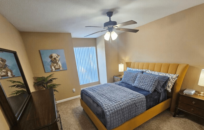 A bedroom with a bed, nightstand, and a ceiling fan.