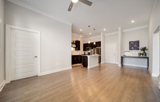 a living room and kitchen with white walls and wood floors