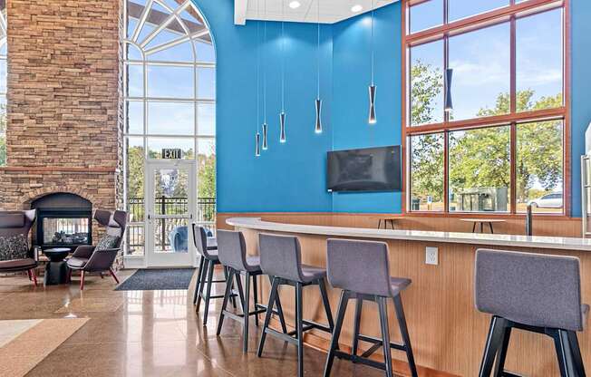a lobby with a bar with chairs and a fireplace