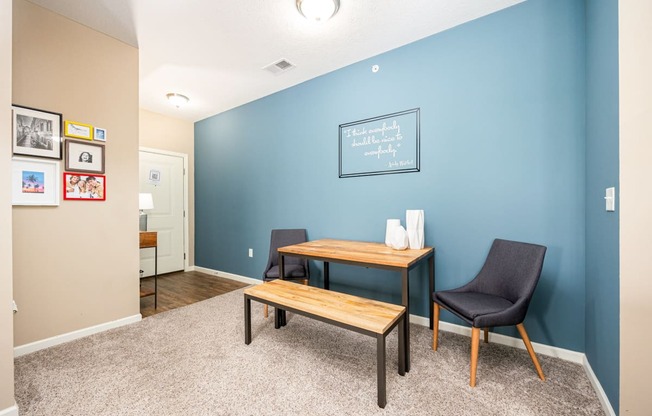 a home office with a blue wall and a desk with a chair and a table