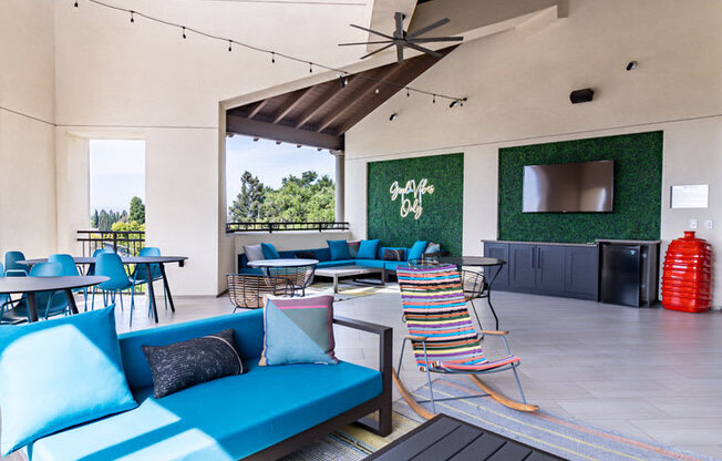 a patio with blue couches and chairs and tables and a tv