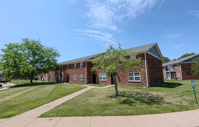 a brick building with grass and trees in front of it