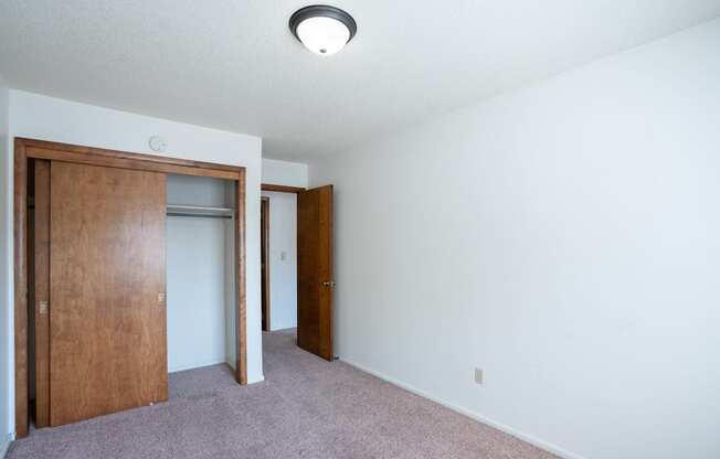 an empty room with a closet and a door to a bedroom. Fargo, ND Betty Ann Apartments