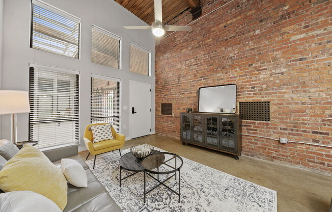 a living room with a large brick wall and a ceiling fan