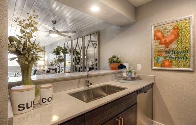 A kitchen with a white counter top and a painting on the wall.