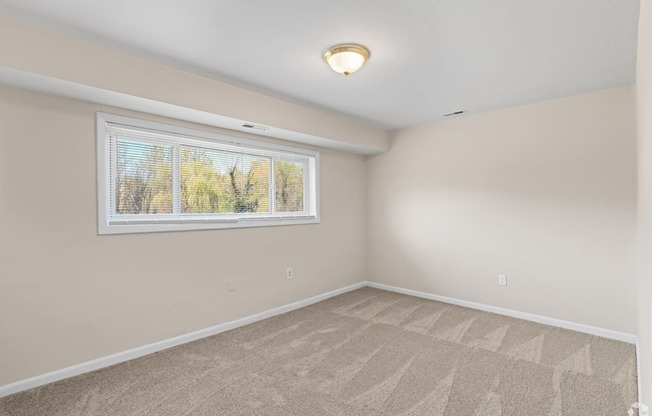 A room with a window and carpeted floor.