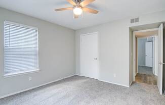 A room with a ceiling fan and carpeted floor.