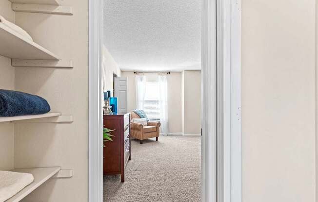 A hallway with a chair and a plant in the background.