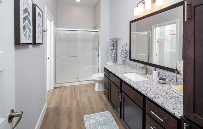 A bathroom with a toilet, sink, and mirror.