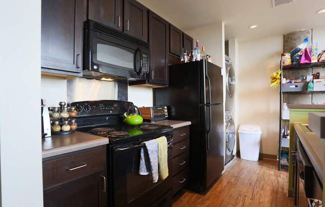 A kitchen with black appliances and wooden floors.