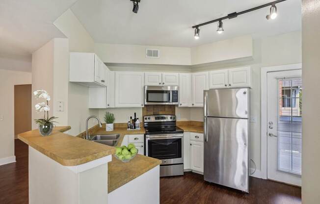 A modern kitchen with stainless steel appliances and wooden floors.