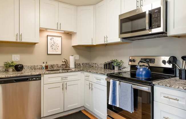 A modern kitchen with white cabinets and stainless steel appliances.