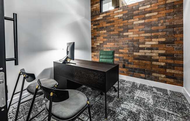 a home office with a desk and chairs and a brick wall