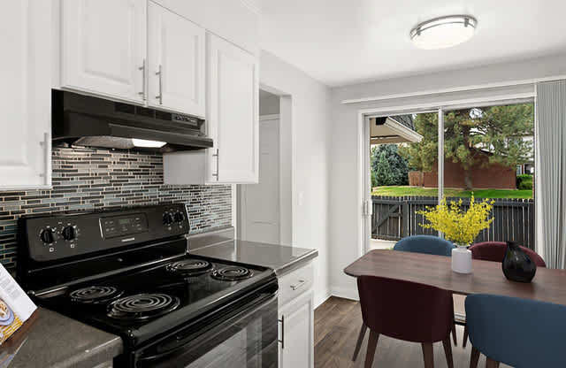 A modern kitchen with a black stove top oven and white cabinets.