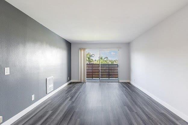 A room with grey walls and wooden flooring with a window and a door.