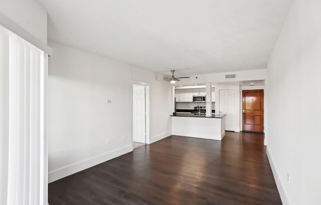 A spacious living room with faux wooden floors and white walls.